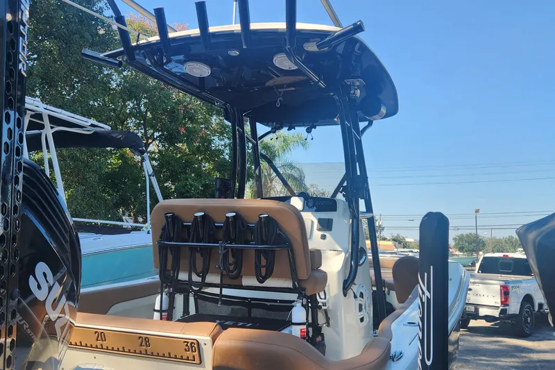 Slide: The Image of 2022 Pioneer 222 Islander boat with seating and fishing rod holders, parked outdoors. - 5