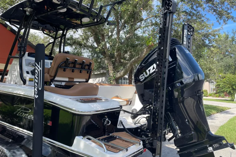Slide: The Image of 2022 Pioneer 222 Islander boat with Suzuki engine, parked outdoors under trees. - 9
