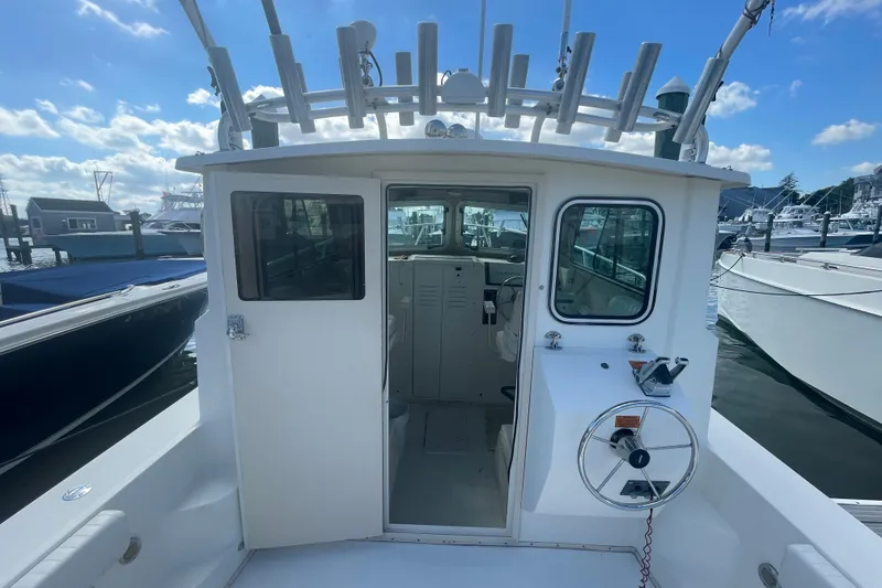 Slide: The Image of 2007 Parker 2820 XLD Sport Cabin boat docked, showcasing cabin entrance and steering wheel. - 13