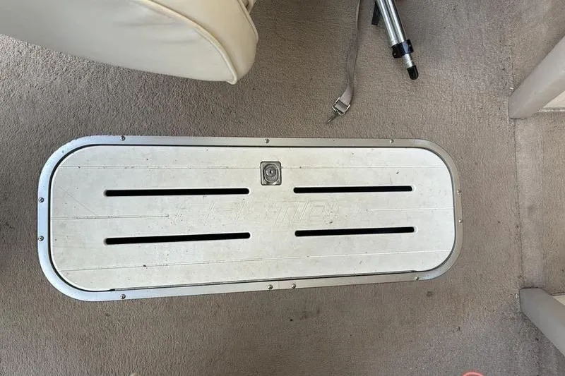 Slide: The Image of Floor compartment on a 1999 Ebbtide 2300 boat, featuring a metal hatch and carpeted surface. - 10