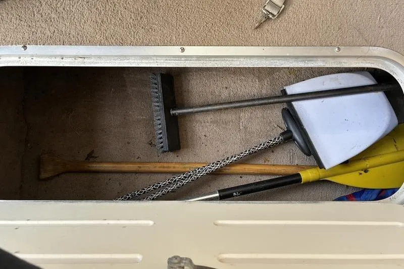 Slide: The Image of Storage compartment in a 1999 Ebbtide 2300 boat with cleaning tools and paddles. - 11