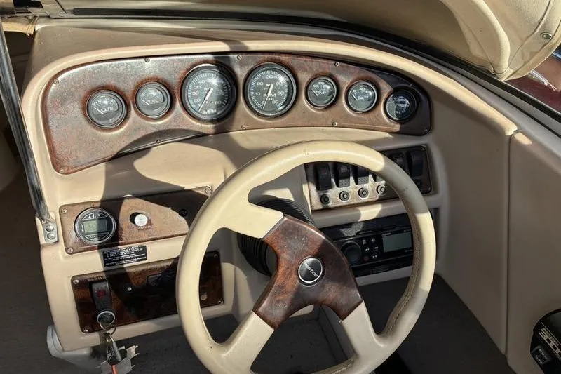 Slide: The Image of 1999 Ebbtide 2300 boat dashboard with gauges, steering wheel, and control panel. - 26