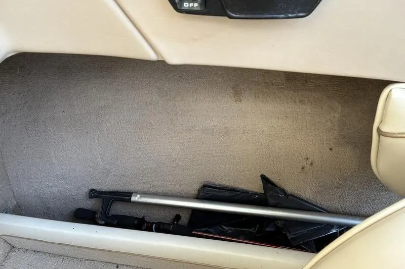 Slide: The Image of 1999 Ebbtide 2300 interior storage compartment with umbrella and rod. - 29