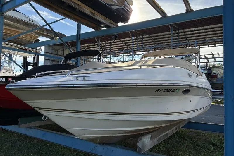 Slide: The Image of 1999 Ebbtide 2300 boat in storage, white exterior, parked on a metal rack. - 4