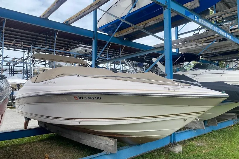 The Image of 1999 Ebbtide 2300 boat stored on a rack, covered and secured. - 1