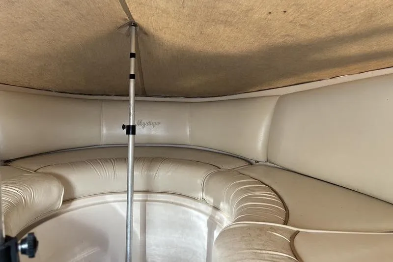 Slide: The Image of 1999 Ebbtide 2300 boat interior with beige seating and canopy support pole. - 18