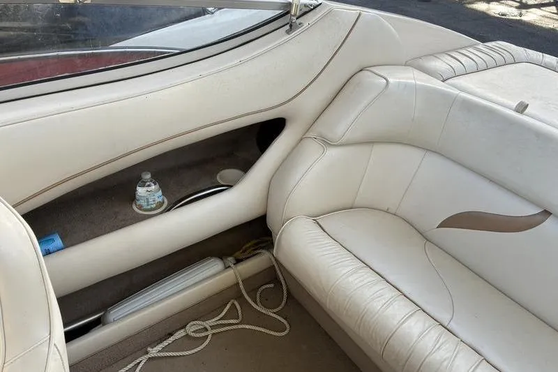 Slide: The Image of 1999 Ebbtide 2300 boat interior with white leather seating and storage area. - 39