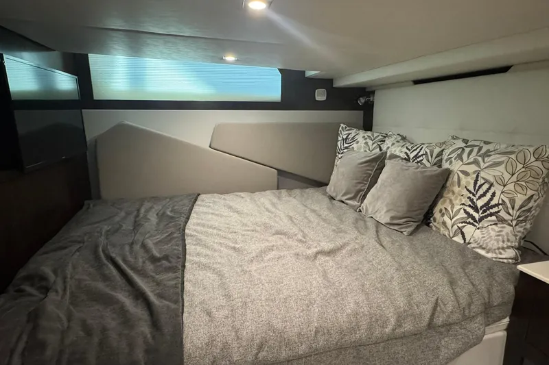 Slide: The Image of 2022 Cruisers Yachts 390 Express Coupe interior cabin with cozy bed and decorative pillows. - 9