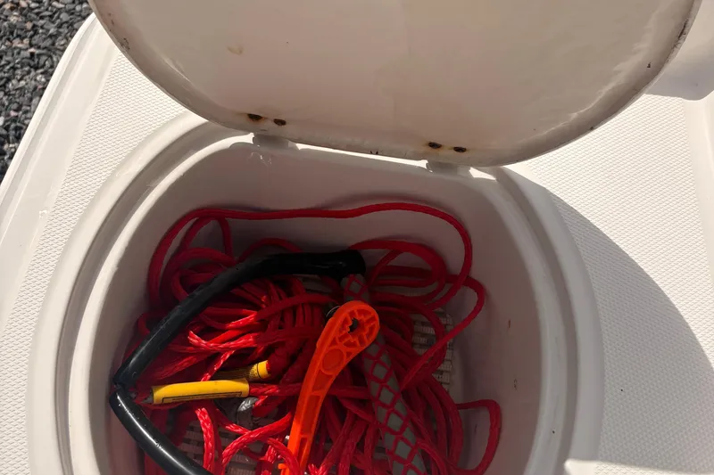 Slide: The Image of Open storage compartment on 2011 Monterey 204FS boat with red rope and accessories. - 12