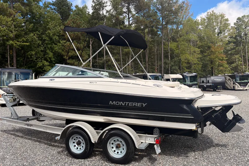 Slide: The Image of 2011 Monterey 204FS boat on trailer, parked outdoors with trees in background. - 24
