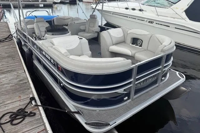 Slide: The Image of 2015 Sylvan Mirage Cruise 8522 LZ pontoon boat docked, featuring spacious seating and sleek design. - 9