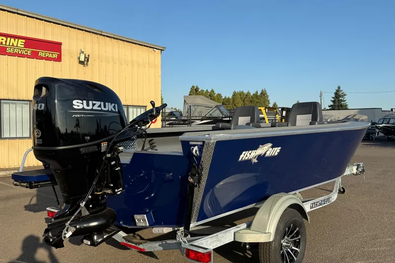 Slide: The Image of 2026 Fish Rite River Master 18 boat with Suzuki outboard motor, parked outside a service shop. - 3