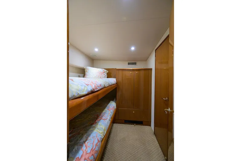 Slide: The Image of 2004 Viking 48 Convertible yacht cabin with bunk beds and wooden cabinetry. - 48