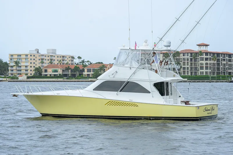 Slide: The Image of 2004 Viking 48 Convertible yacht on water near luxury waterfront buildings. - 8