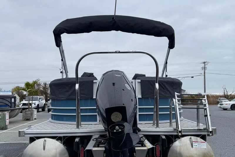 Slide: The Image of 2025 Berkshire 24RFX LE 2.75 pontoon boat with outboard motor, parked outdoors. - 17