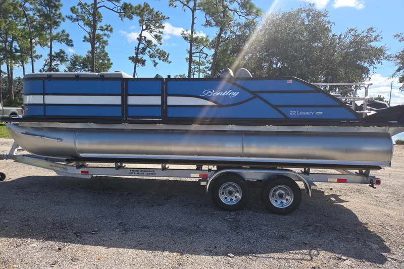 Slide: The Image of 2026 Bentley Pontoons 223 Swingback on trailer, parked outdoors under sunny sky. - 3