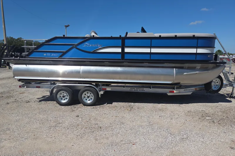 Slide: The Image of 2026 Bentley Pontoons 223 Swingback on trailer, blue and silver design, parked outdoors. - 4