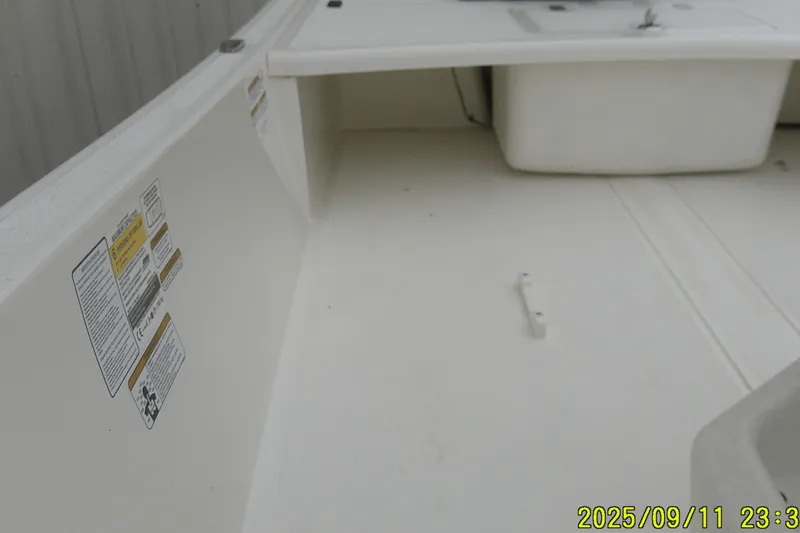 Slide: The Image of 2025 Mako Pro Skiff 17 CC interior with storage compartment and safety labels. - 16