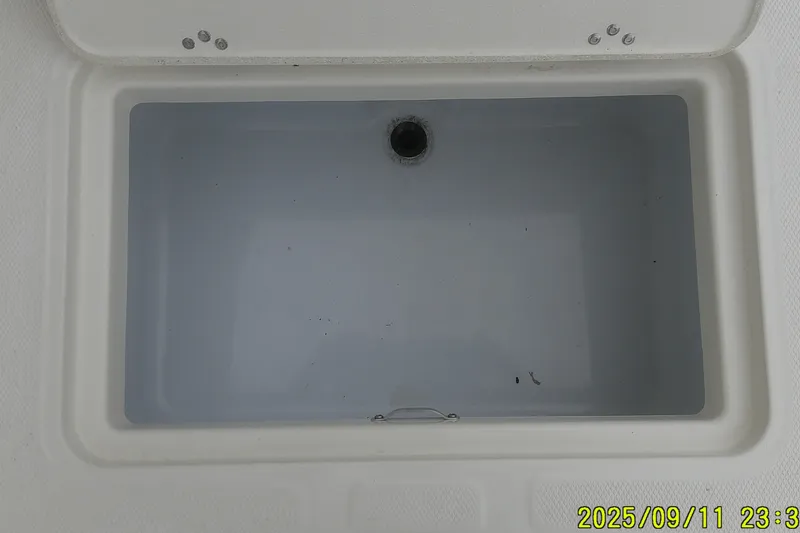 Slide: The Image of Livewell compartment of 2025 Mako Pro Skiff 17 CC boat, open lid view. - 17