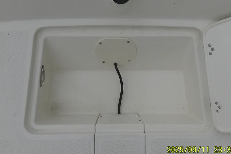 Slide: The Image of Storage compartment of 2025 Mako Pro Skiff 17 CC boat, featuring a cable and handle. - 6