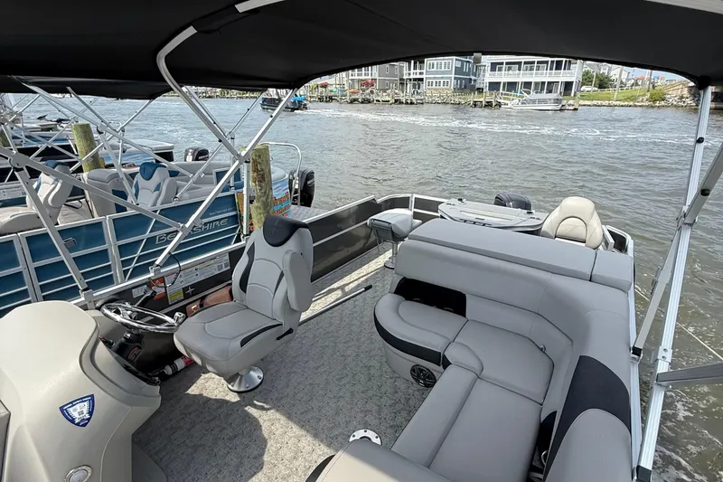 Slide: The Image of 2025 Berkshire 24RFC LE 2.75 pontoon boat with outboard motor, parked outdoors. - 7