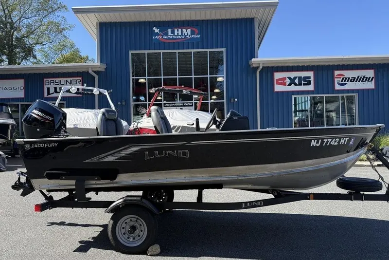 The Image of 2023 Lund 1400 Fury SS boat on trailer outside marine dealership. - 1