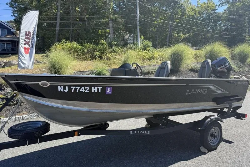 Slide: The Image of 2023 Lund 1400 Fury SS boat on trailer, parked outdoors, with Mercury engine. - 12