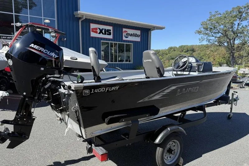 Slide: The Image of 2023 Lund 1400 Fury SS boat with Mercury engine on trailer, parked outside dealership. - 8