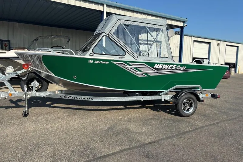 The Image of 2025 Hewescraft 180 Sportsman boat on trailer, green exterior, parked outdoors. - 1