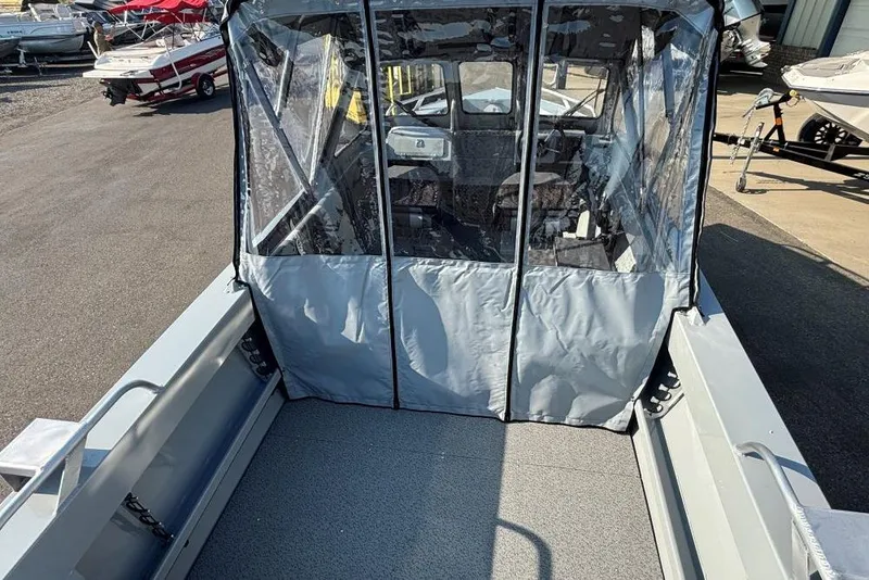 Slide: The Image of 2025 Hewescraft 180 Sportsman boat with covered cabin, docked outdoors. - 3