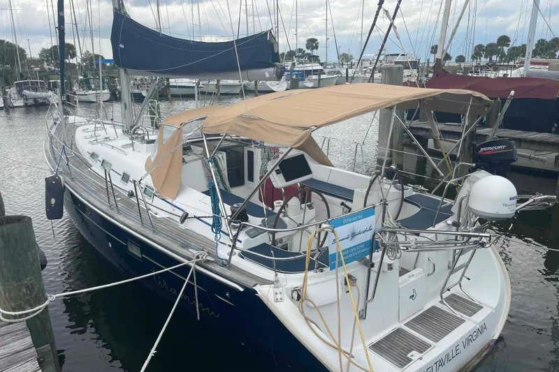 Slide: The Image of 2004 Beneteau Oceanis 473 sailboat docked at marina, featuring tan canopy and sleek design. - 108