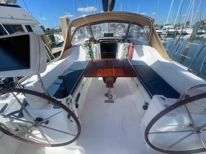 Slide: The Image of 2004 Beneteau Oceanis 473 sailboat cockpit with dual steering wheels and wooden table. - 49