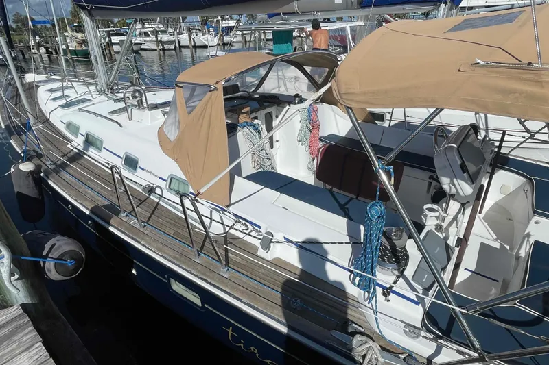 Slide: The Image of 2004 Beneteau Oceanis 473 sailboat docked at marina, featuring tan canopy and sleek design. - 80