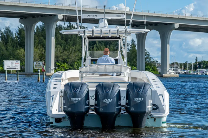 Slide: The Image of 2011 Bahama 37 boat with triple Yamaha engines under a bridge on a sunny day. - 4