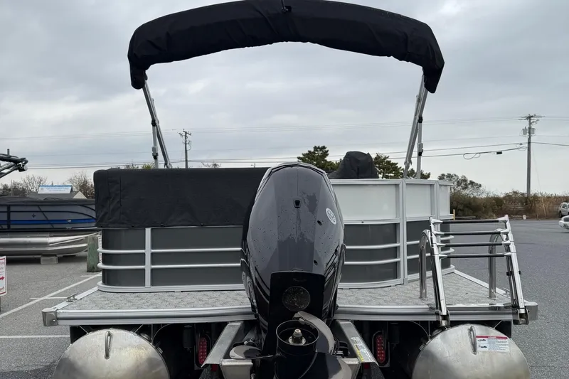 Slide: The Image of 2025 Berkshire 24CL 2.75 LE pontoon boat with open storage compartment, docked alongside other boats. - 12