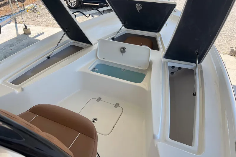 Slide: The Image of 2026 Key West 230 Bay Reef boat interior with open storage compartments and seating. - 15