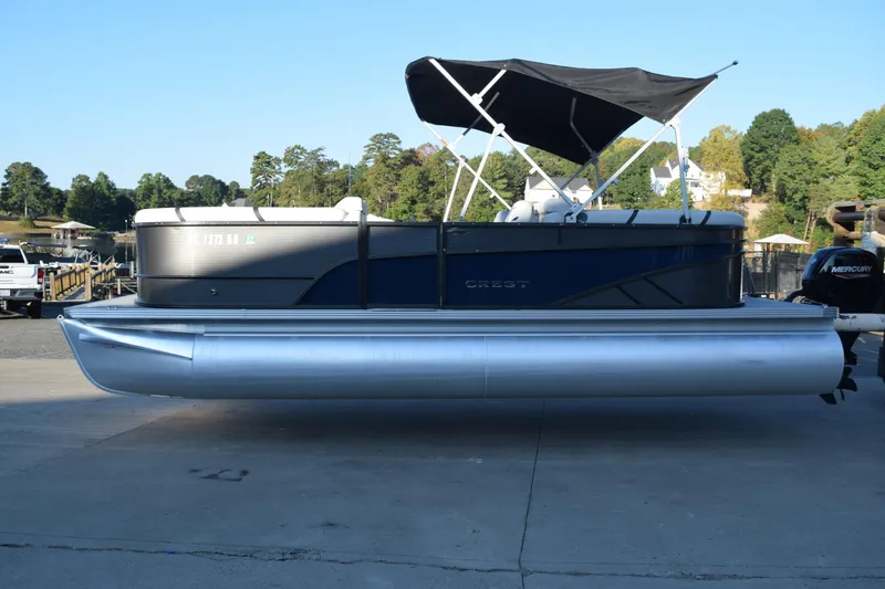 The Image of 2024 Crest Classic LX 220 SLC pontoon boat with canopy, docked outdoors. - 1