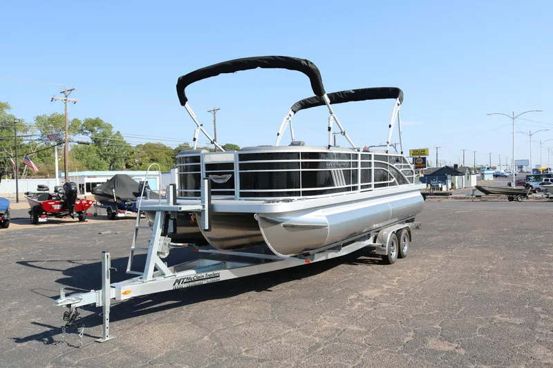Slide: The Image of 2026 Bennington 22SX Stern Radius pontoon boat on trailer, parked outdoors under clear sky. - 3