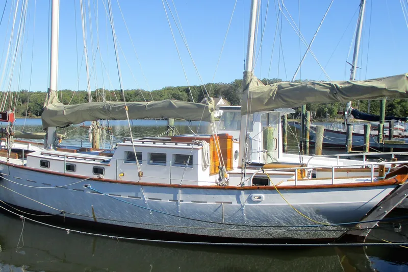 The Image of Custom Gaff Rigged Ketch, 1955 model, docked in a serene marina setting. - 0