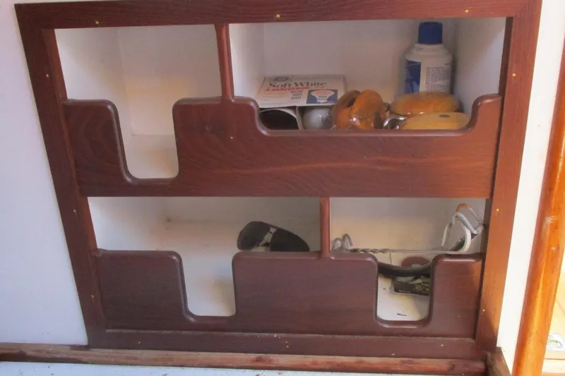 Slide: The Image of Wooden storage shelves on a 1955 Custom Gaff Rigged Ketch, holding nautical items. - 14