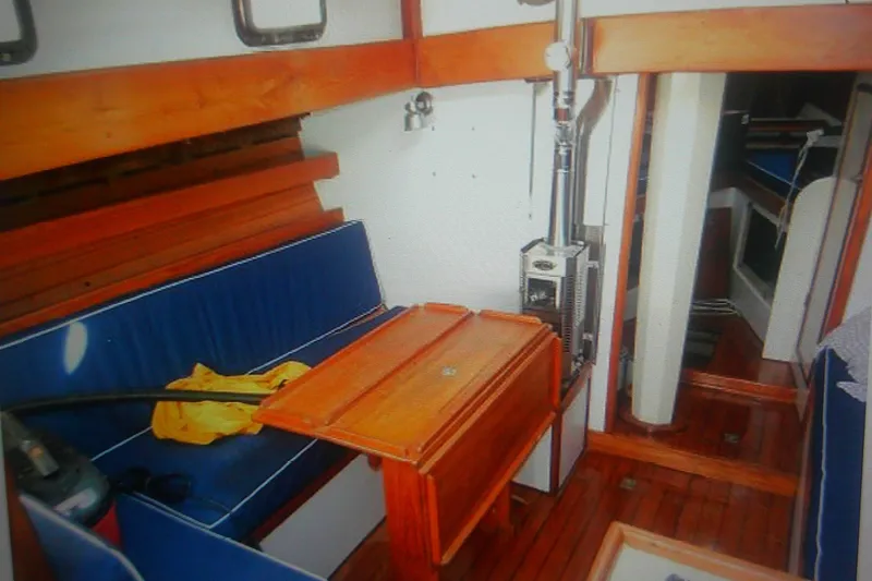 Slide: The Image of Interior of 1955 Custom Gaff Rigged Ketch with wooden furnishings and blue seating. - 19