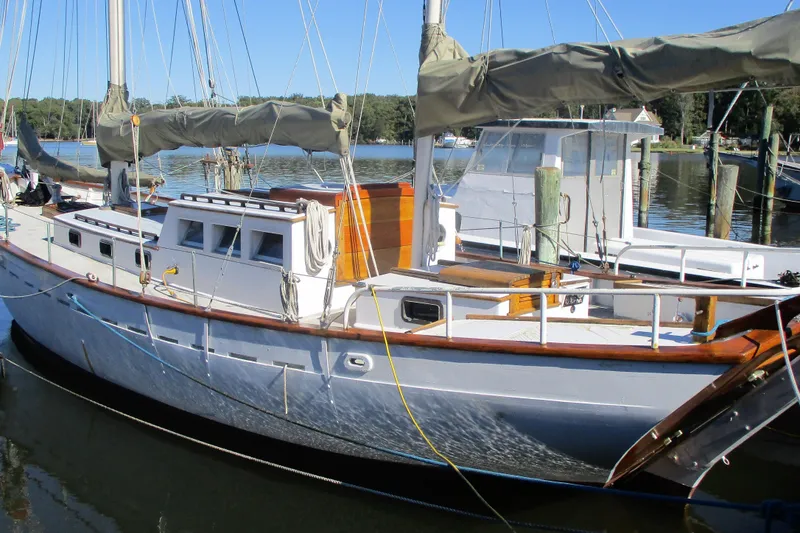 Slide: The Image of 1955 Custom Gaff Rigged Ketch, full keel, docked in a serene marina setting. - 2