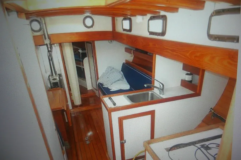 Slide: The Image of Interior of 1955 Custom Gaff Rigged Ketch with wooden finishes and compact kitchen area. - 22