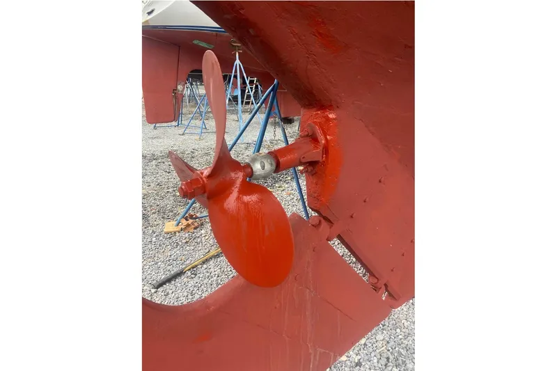 Slide: The Image of Propeller of 1955 Custom Gaff Rigged Ketch, freshly painted red, on gravel surface. - 47