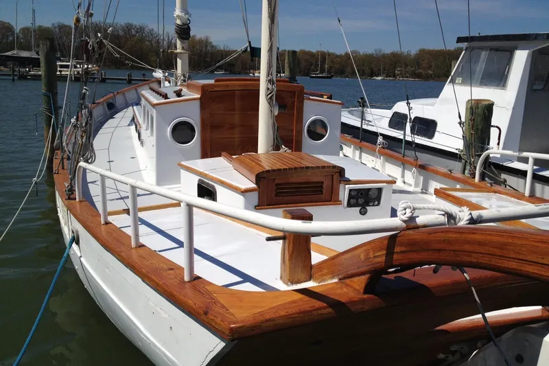 Slide: The Image of Classic 1955 Custom Full Keel Ketch with wooden deck and white hull, docked in marina. - 55