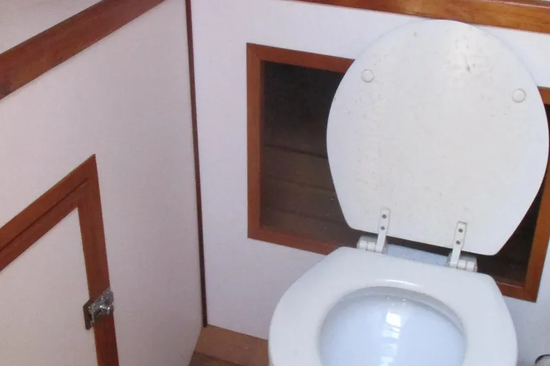 Slide: The Image of 1955 Custom Gaff Rigged Ketch bathroom with white toilet and wooden trim. - 7