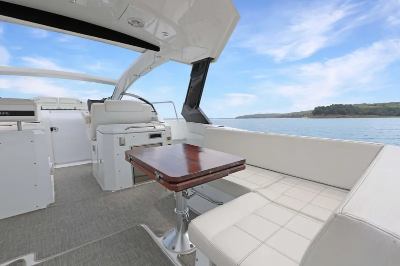 Slide: The Image of 2018 Cruisers Yachts 390 EC interior with seating and table, overlooking serene water and sky. - 23
