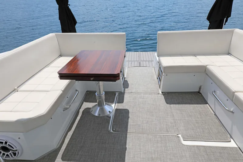 Slide: The Image of 2018 Cruisers Yachts 390 EC deck with seating and wooden table, overlooking the ocean. - 40
