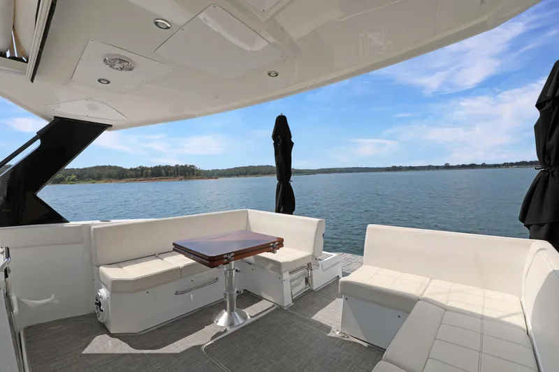Slide: The Image of 2018 Cruisers Yachts 390 EC interior with seating and table, overlooking serene water view. - 27