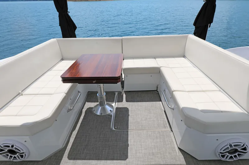 Slide: The Image of Luxury seating area on 2018 Cruisers Yachts 390 EC, featuring white cushions and wooden table. - 41